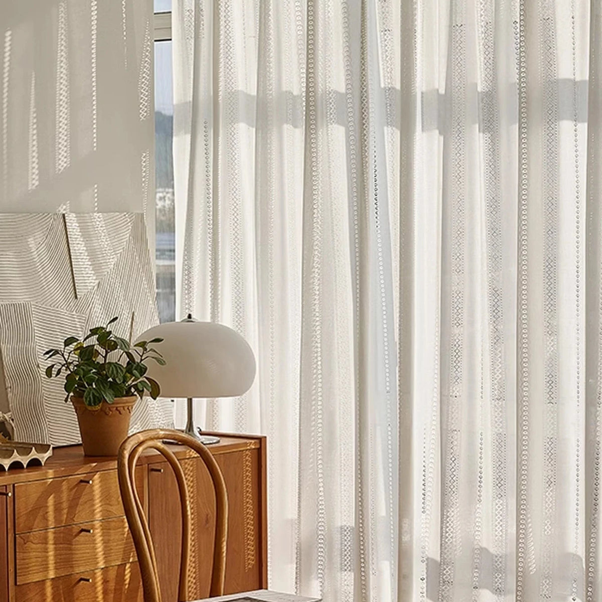 White lace sheer curtain filtering sunlight in a room with a wooden dresser and chair, CD1049