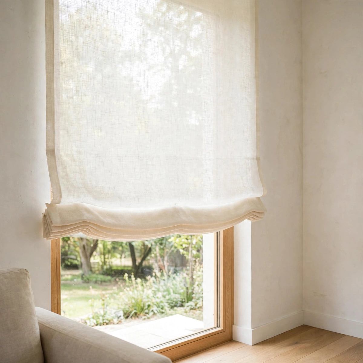 Ivory sheer linen flat Roman shade seen at an angle, raised partway over a garden window