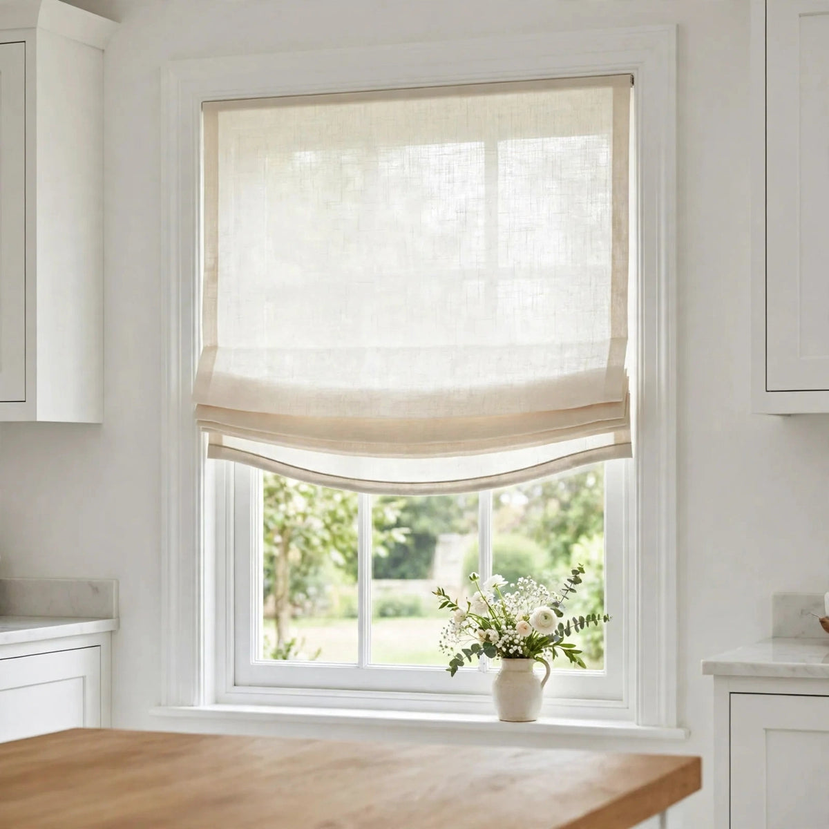 Ivory sheer linen relaxed Roman shade half raised in a bright kitchen