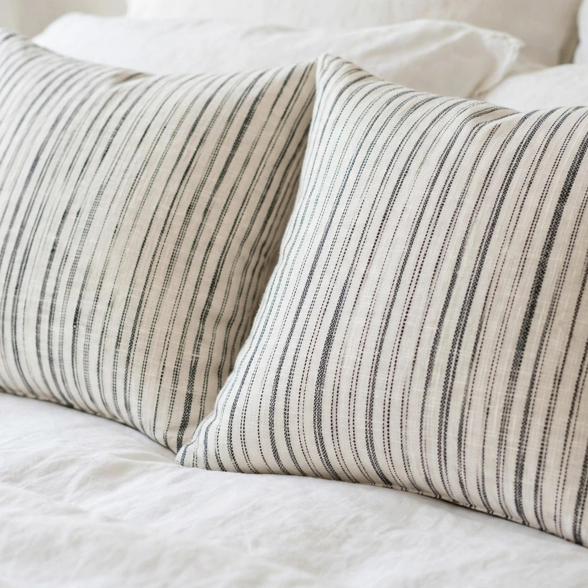 Narrow striped linen bed pillow covers on white sheets