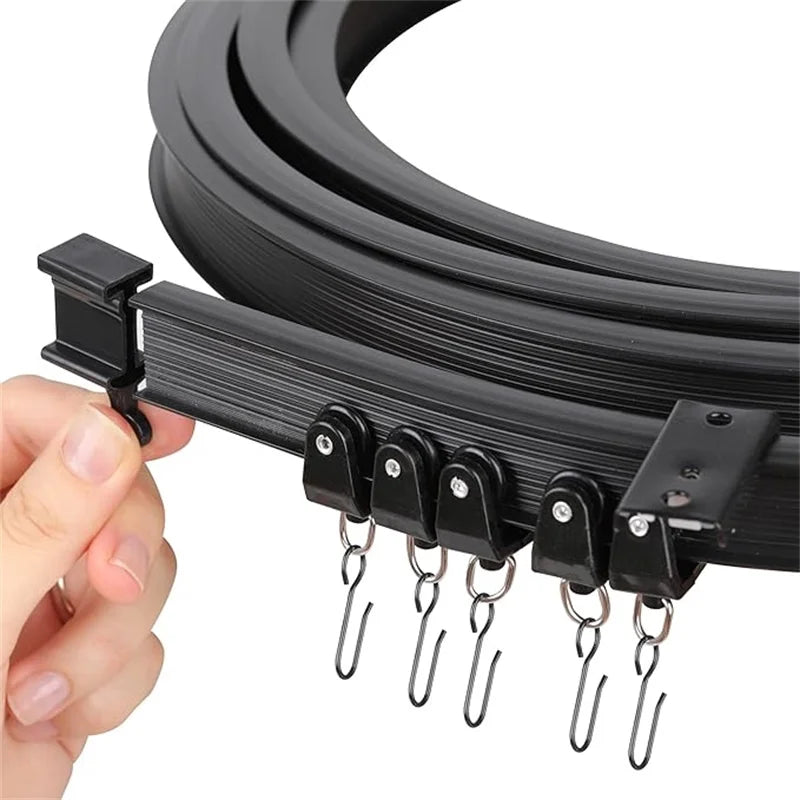 Close-up of a hand holding the black flexible curtain track with rollers and stainless steel hooks