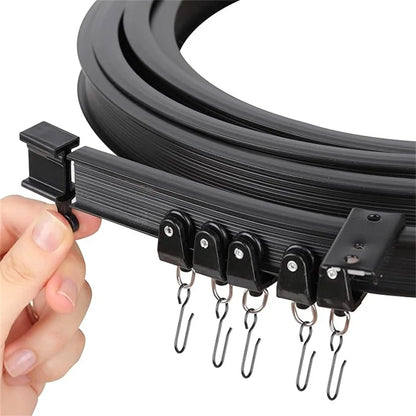 Close-up of a hand holding the black flexible curtain track with rollers and stainless steel hooks