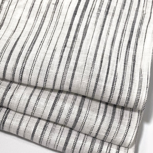 Close-up of a folded piece of linen fabric with a narrow irregular stripe pattern.