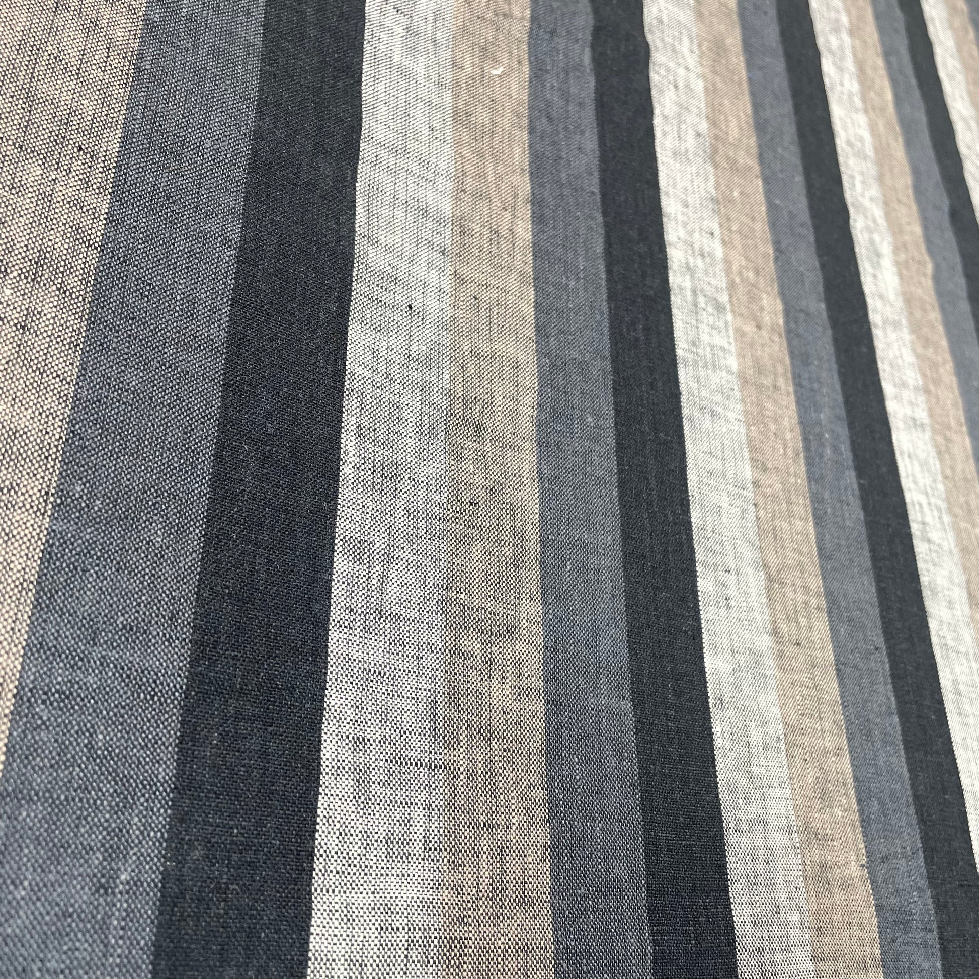 Natural linen fabric with dark vertical stripes in black, gray, and beige tones, laid flat.