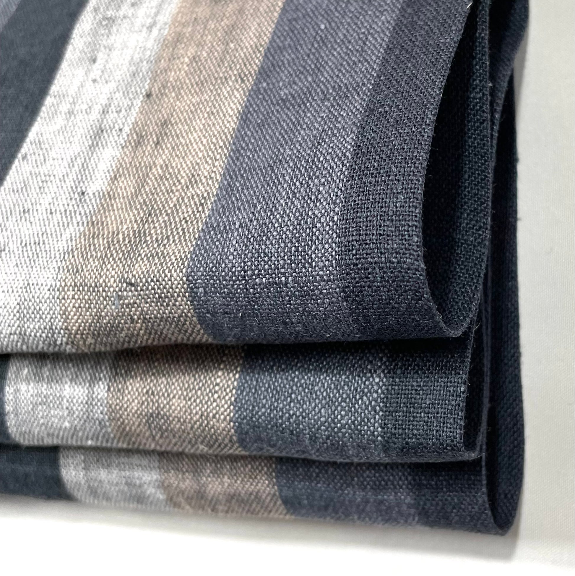 Natural linen fabric roman shade with dark vertical stripes in black, gray, and beige tones