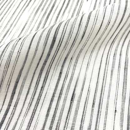 Natural linen fabric with narrow black irregular stripes on an ivory background, shown with gentle folds.