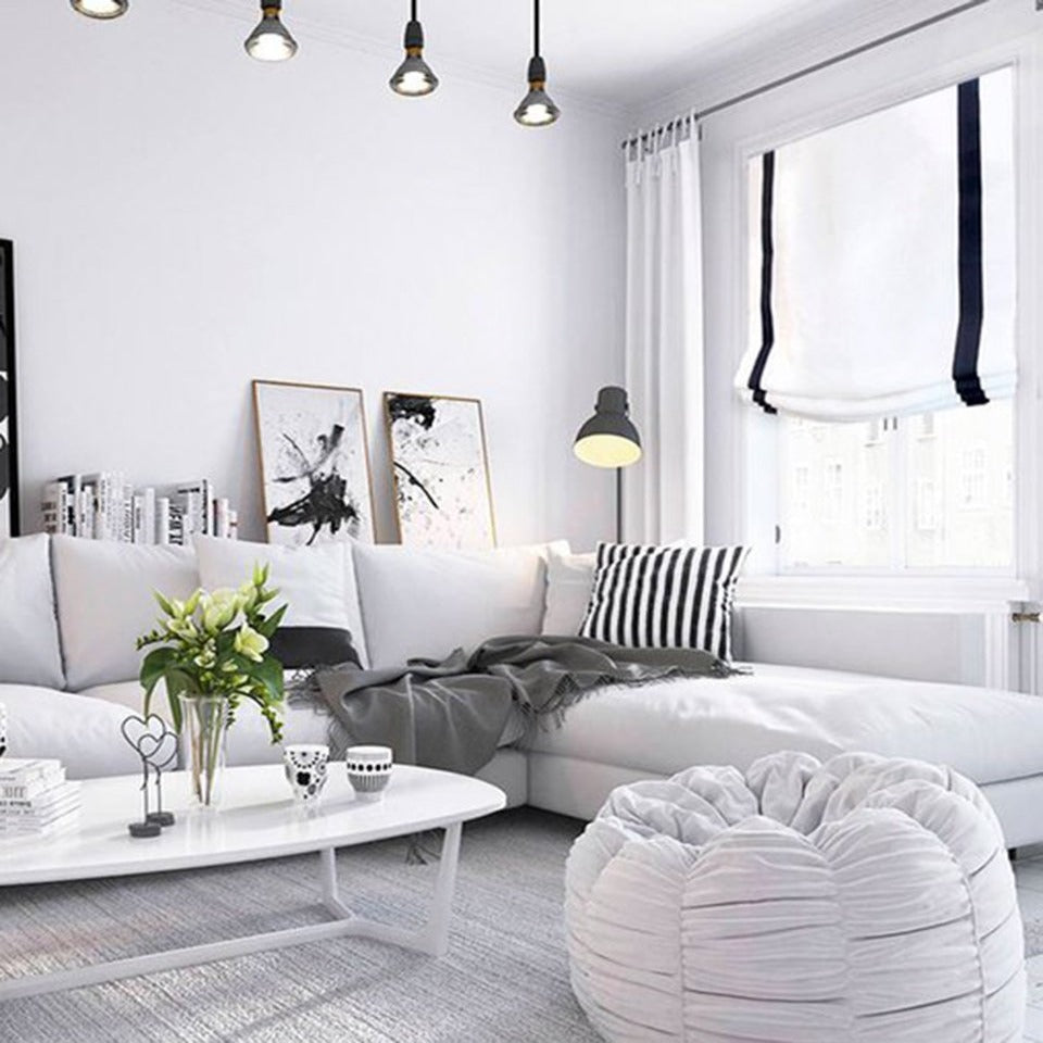 White linen roman shade with black border on living room. 