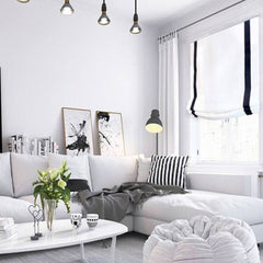 White relaxed roman shade with black band in cozy white interior living room 