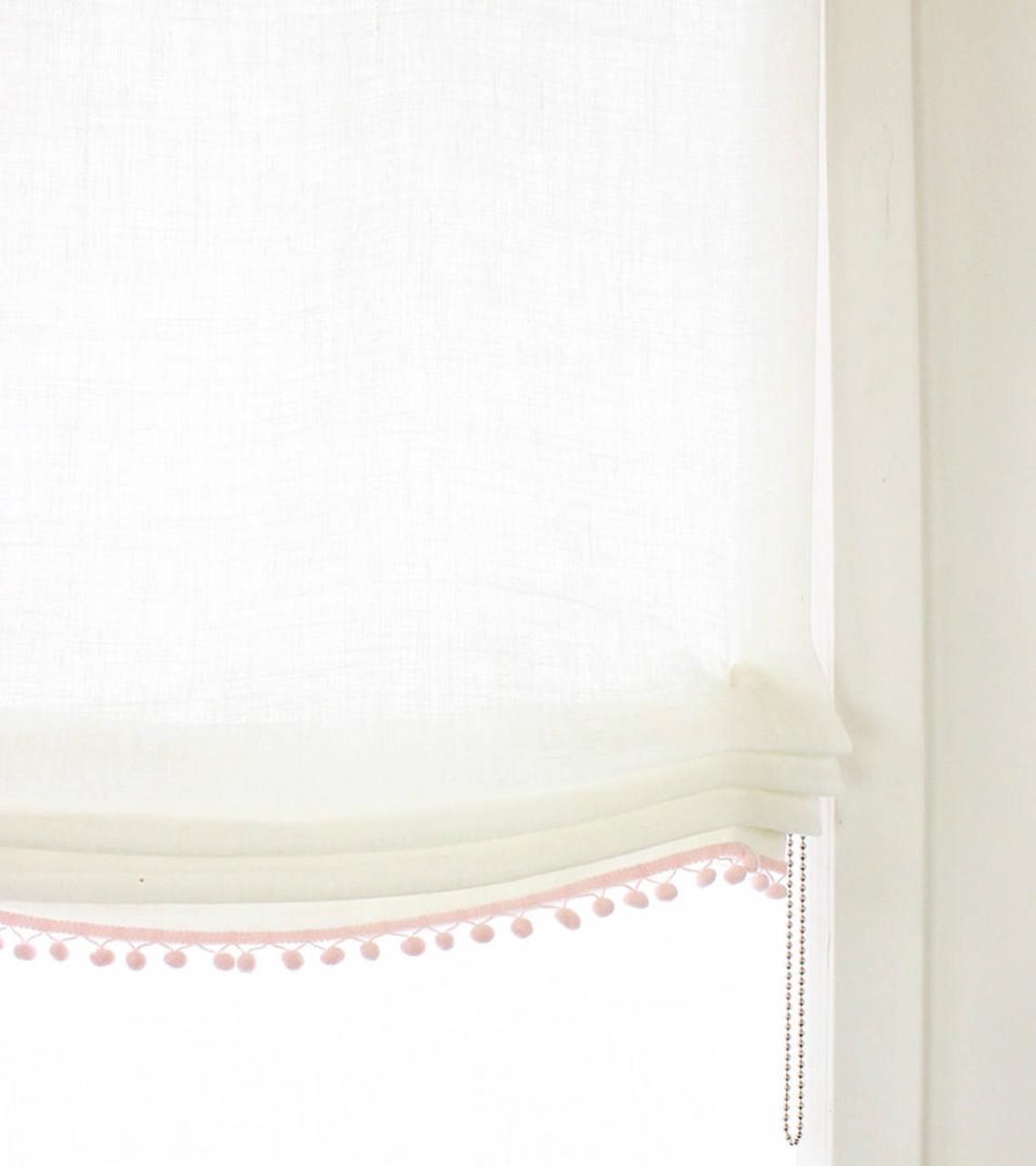 white linen relaxed roman shade with pink pom pom
